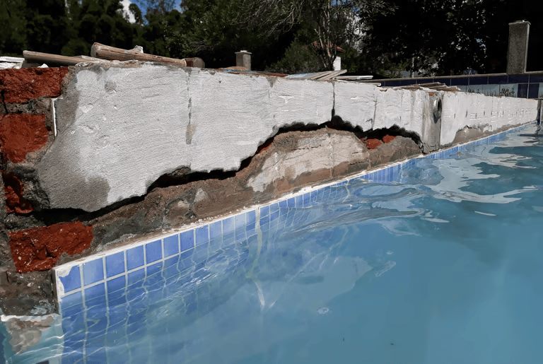 Parede da piscina danificada com trincas antes do conserto